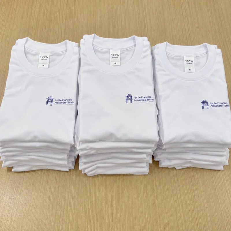 170 áo thun Math en Jeans 2025 – Mẫu MS083 – Áo thun trắng cổ tròn có logo Alexandre Yersin, được gấp thành từng chồng. – 1