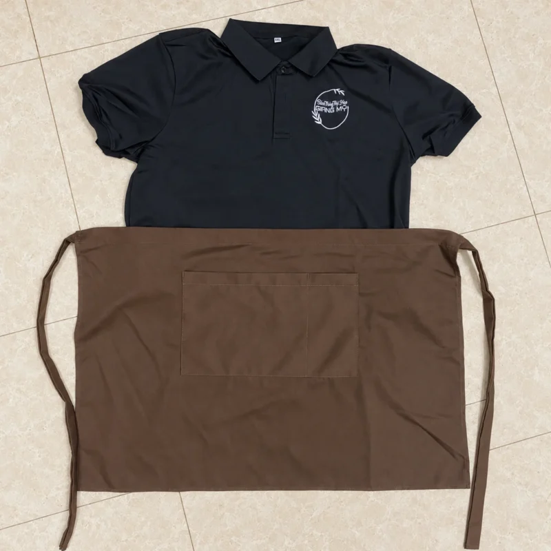 Đồng phục Giang Mỹ: 650 áo polo đen và 500 tạp dề – Mặt trước áo polo đen Giang Mỹ phối tạp dề nâu có túi. – 1