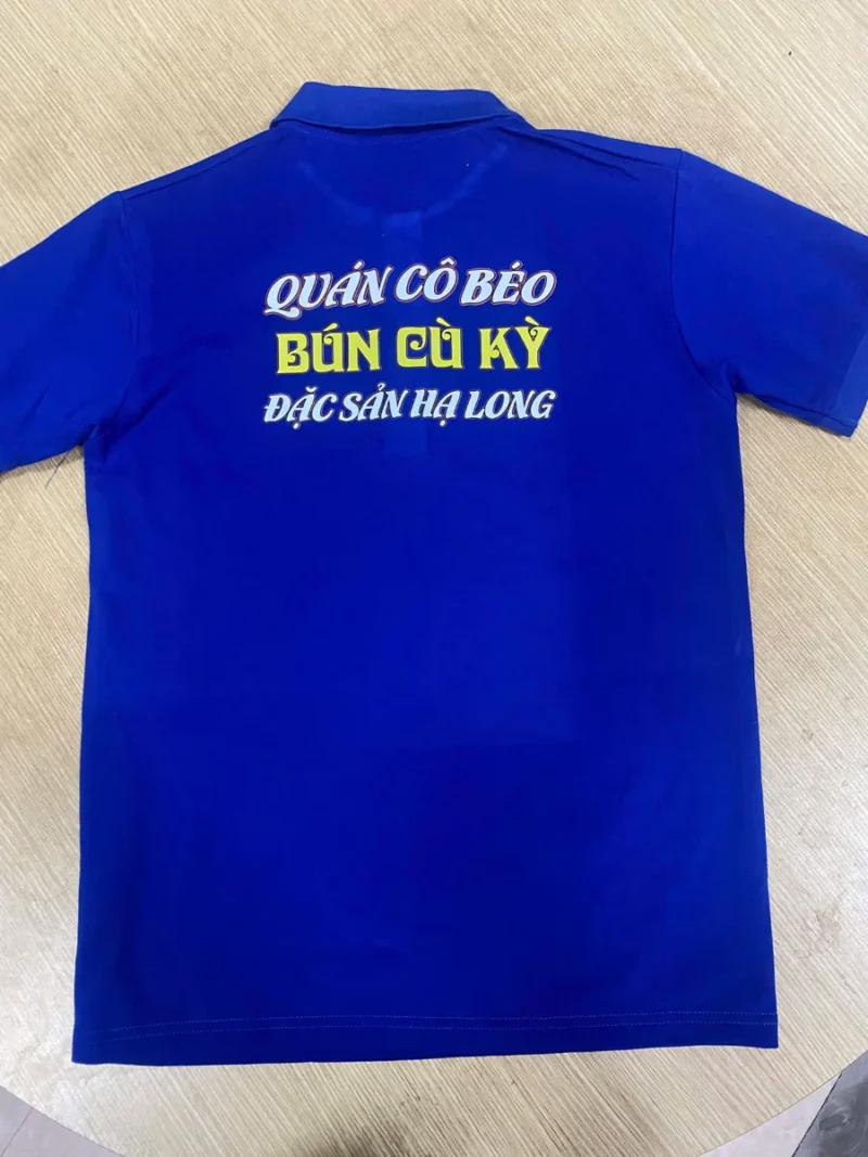 Đồng phục Quán Cô Béo – Áo polo xanh bích và tạp dề – Mặt sau áo polo in Quán Cô Béo – Bún cù kỳ – Đặc sản Hạ Long. – 2