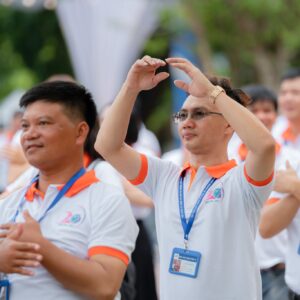 Cựu học sinh K29 mặc áo đồng phục trắng phối cam khi tham gia hoạt động hội khóa ngoài sân trường.