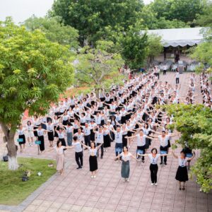 Toàn cảnh cựu học sinh THPT Giao Thủy B mặc áo đồng phục trong hoạt động tập thể tại sân trường.