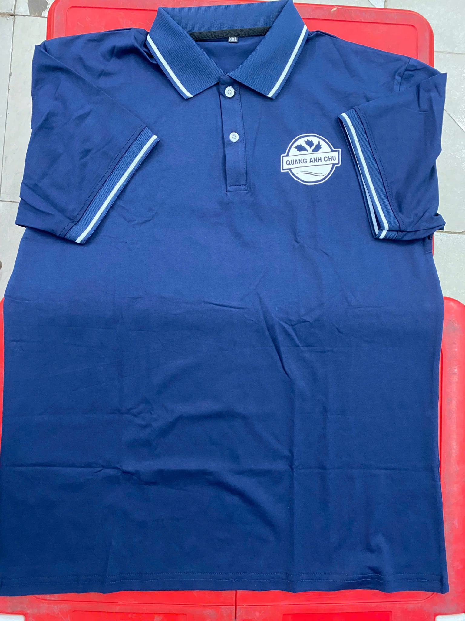 Áo polo xanh đen Airycool với logo QUANG ANH CHU ở ngực trái và viền trắng tại cổ, tay áo. Áo polo xanh đen Airycool với logo QUANG ANH CHU ở ngực trái và viền trắng tại cổ, tay áo.
